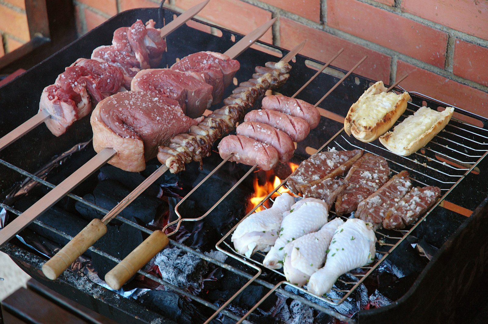 Mesa de churrasco com diferentes carnes na grelha