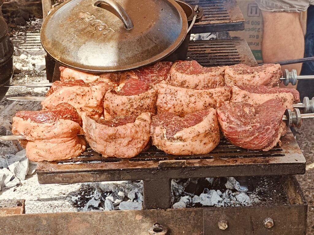 Peca de picanha assando sobre brasas de carvao